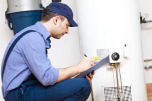 A professional plumber repairing a water heater in a home.